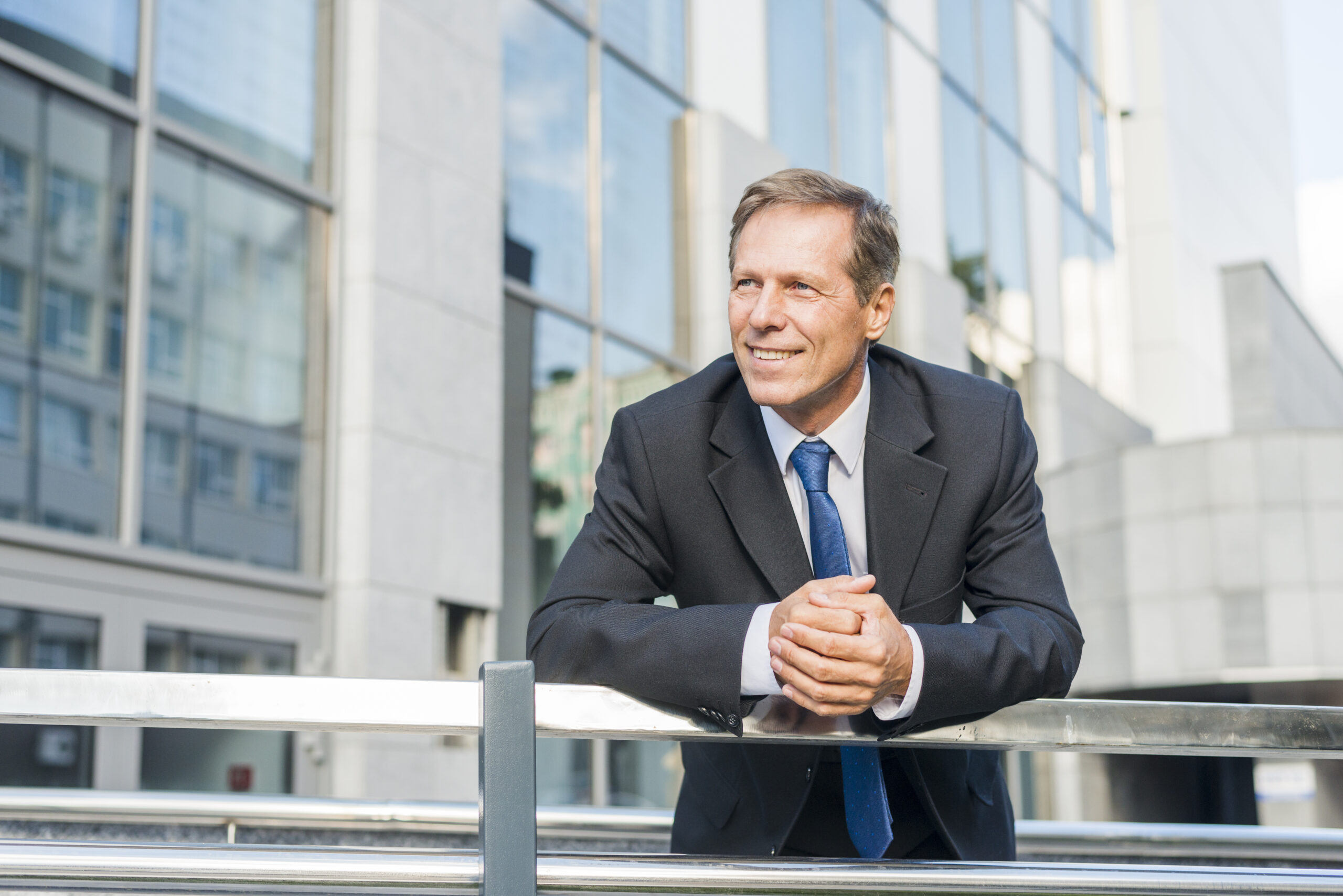 portrait-smiling-mature-businessman-leaning-railing